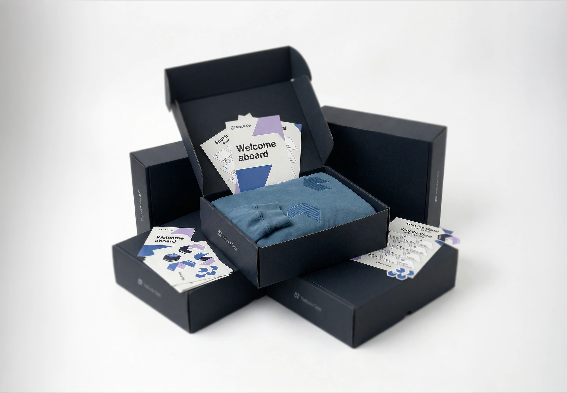 Nebula Ops welcome kit with an open navy box, folded blue hoodie, welcome card and geometric stickers