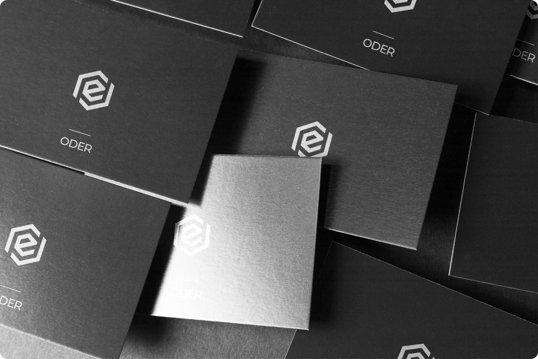 Black ODER business cards with a silver geometric logo and wordmark